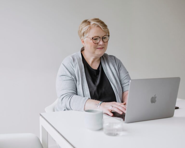 BEM-Beraterin sitzt vor einem Macbook und nimmt an einem Webinar teil