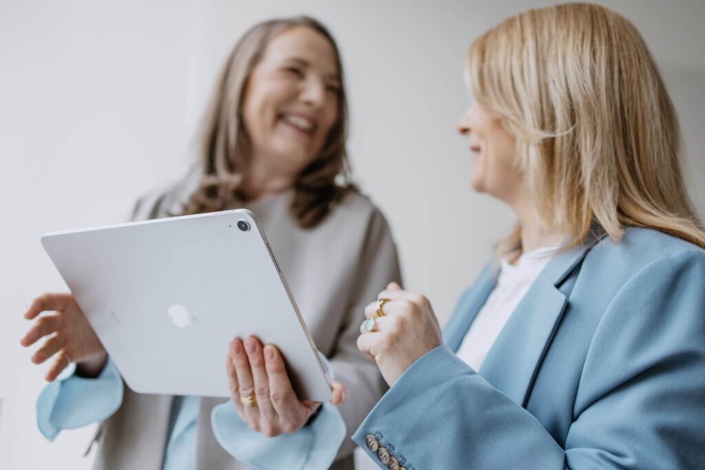 Zwei Mitarbeiterinnen von GIB21 unterhalten sich während sie auf eine iPad schauen