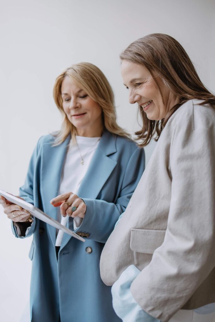 Zwei Frauen schauen gemeinsam auf ein Tablet und unterhalten sich