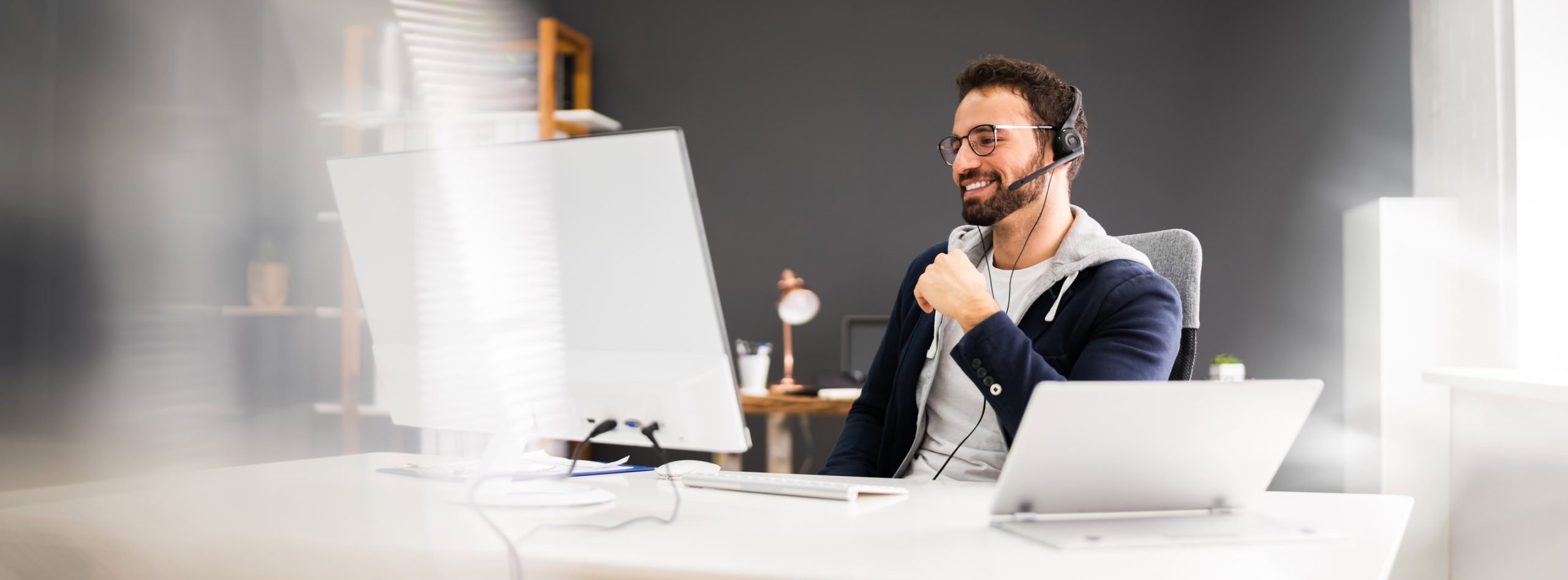 Berater mit Headset arbeitet in Softwareumgebung am Bildschirm