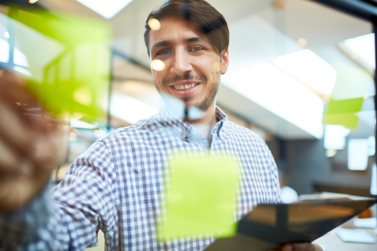 Eine Person hängt Klebezettel an eine durchsichtige Wand.