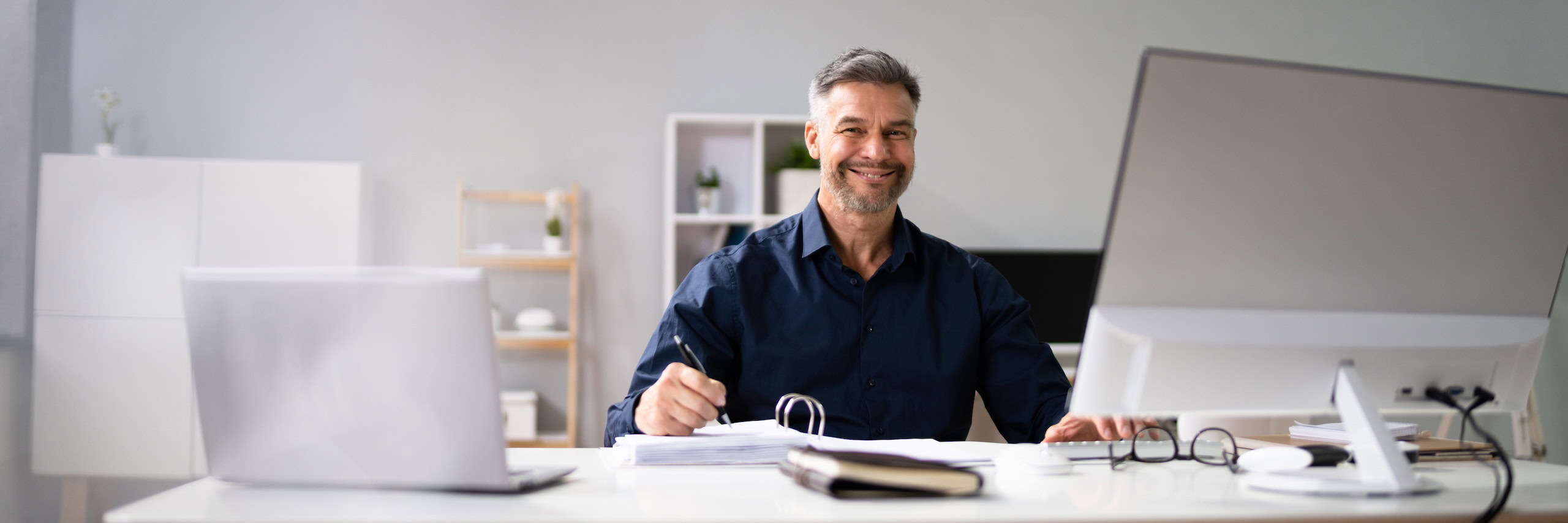Ein Mann sitzt am Schreibtisch und schaut zum Betrachter